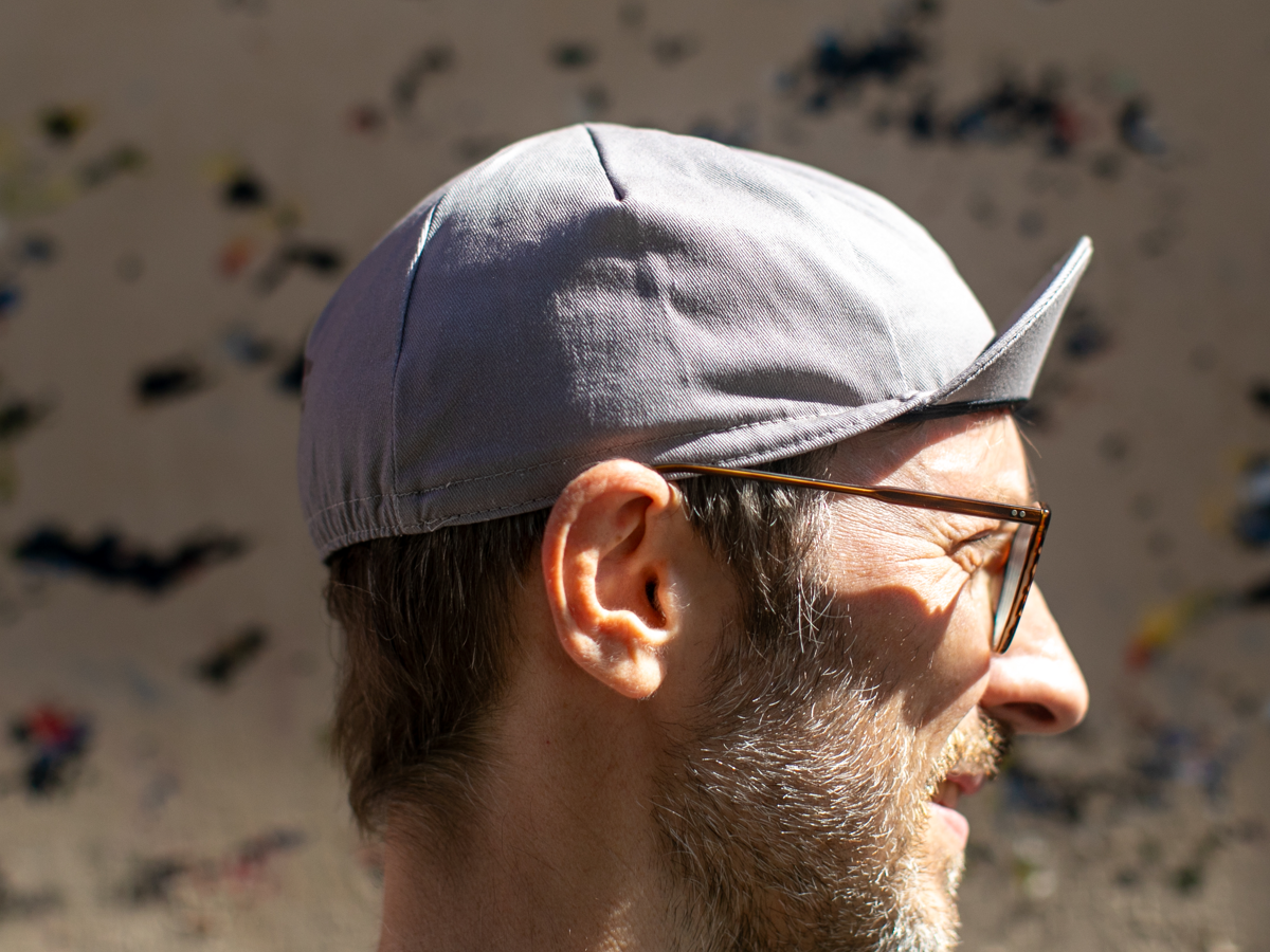 Profil de la casquette de cyclisme Blue Lug Muji coloris gris, montrant la silhouette pointue caractéristique et le tissu uni.