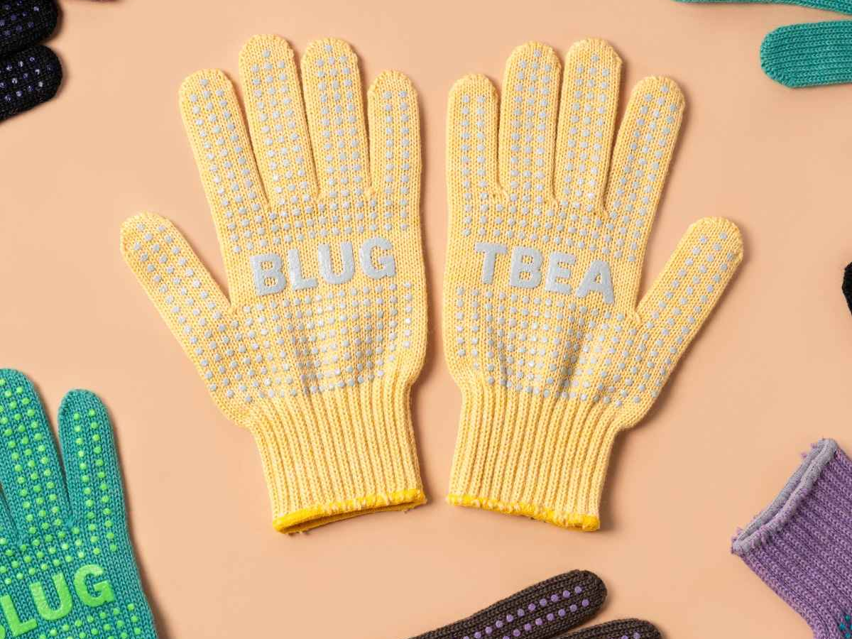 Blue Lug x Tembea merino wool gloves in light yellow with grey anti-slip dots, flat lay showing both palms