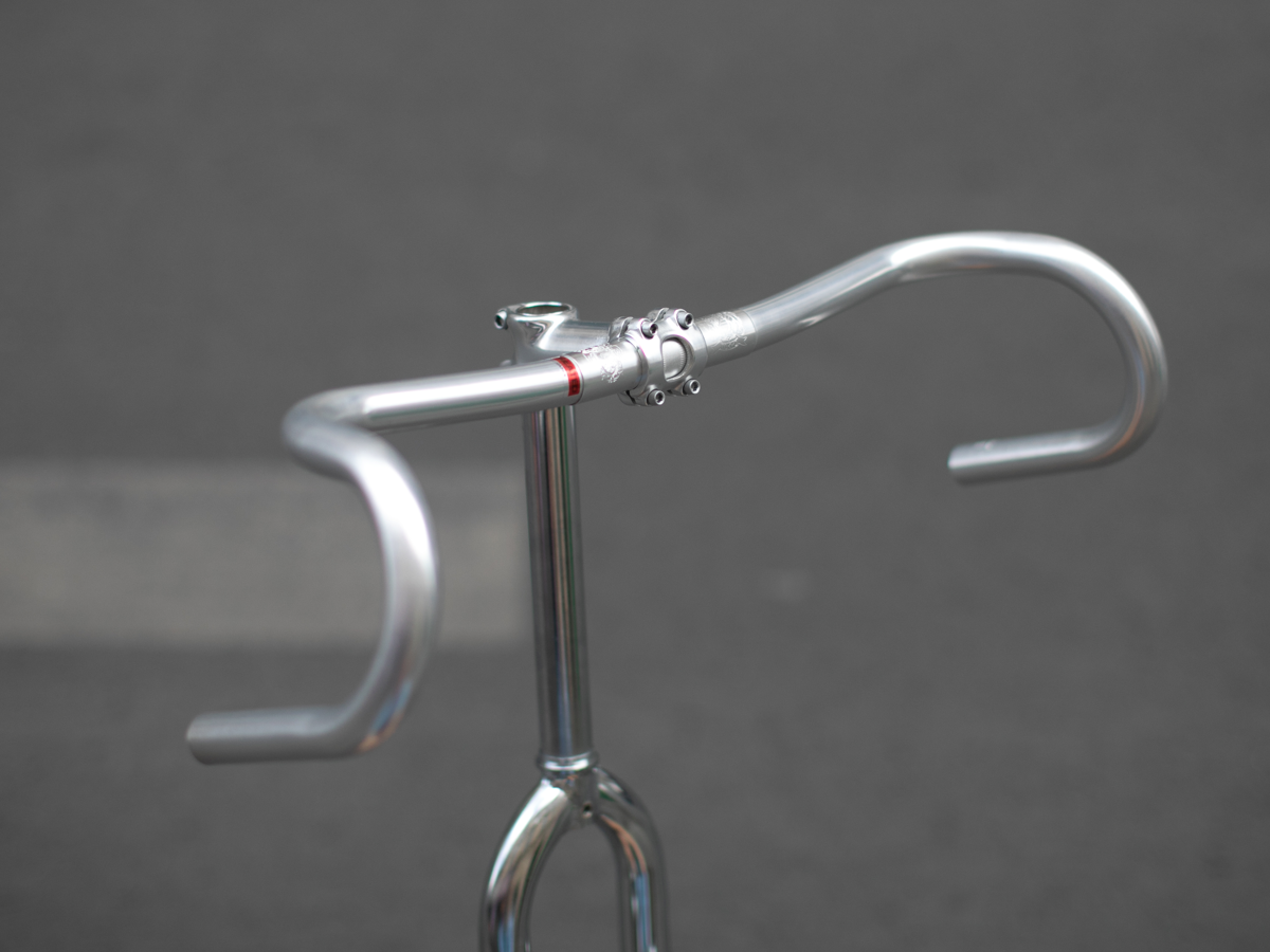 CRUMB x NITTO Futen Drop handlebar three-quarter view, showing randonneur-style sweep, flared drops and polished silver finish on a chrome quill stem
