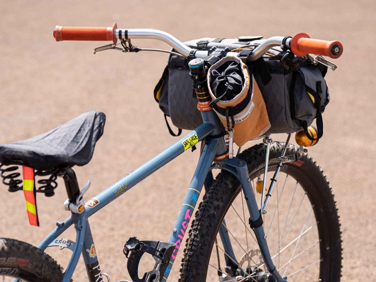 Cintre relevé Nitto B802 AAF-SSB en argent — monté sur un vélo de bikepacking Crust chargé avec sacoches de guidon et poignées orange, fond de terrain extérieur
