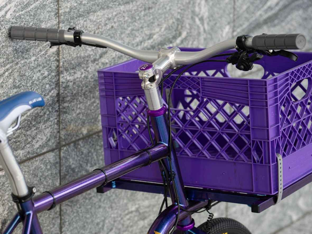Nitto Sync XL silver handlebars mounted on a purple city bike with a front milk crate