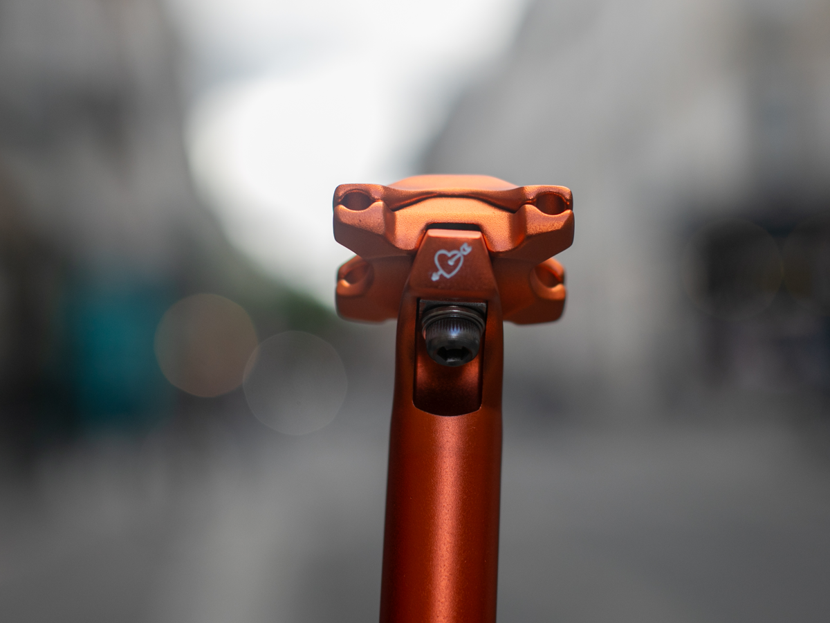 Tige de selle SimWorks Beatnik Sunrise — vue de face de la tête de serrage avec le cœur de cupidon gravé à la main et le boulon de selle, coloris Sunrise orange