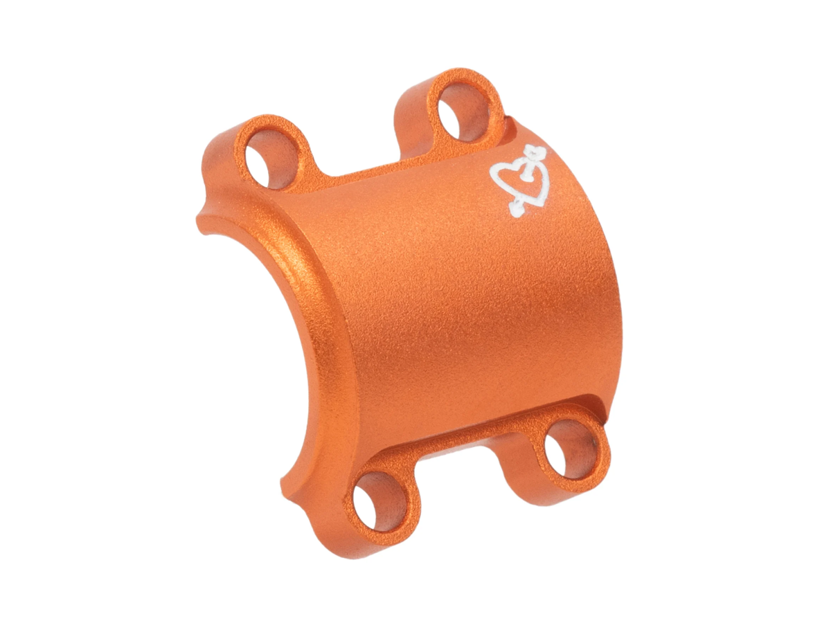 Plaque frontale SimWorks Tomboy coloris Sunrise orange — plaque 4 boulons avec logo cœur et flèche gravé en blanc, sur fond blanc